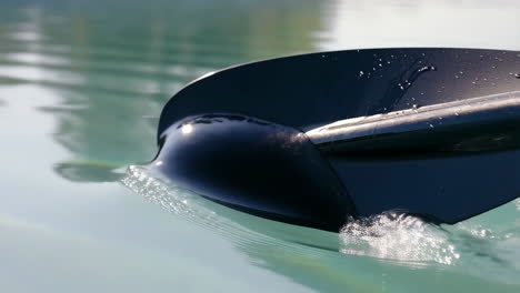paddle dipping into clear water, creating splashes and ripples