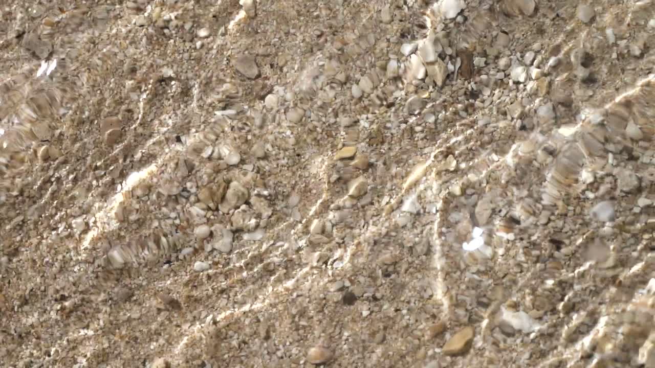 A close up shot of the water rushing onto the beach. Slow motion - 4k