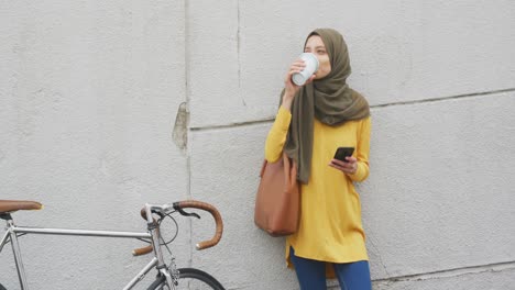 woman wearing hijab drinking in the street with a take away coffee