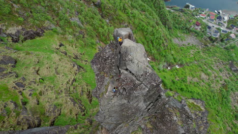 Cinematic-aerial-view-of-a-climber-at-the-top-of-the-rocky-pinnacle-of-Svolvaergeita-in-spring