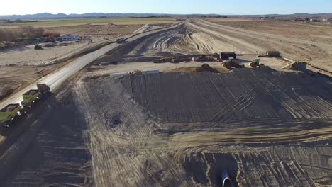 Dramatic-aerial-over-trucks-moving-along-a-highway-under-construction