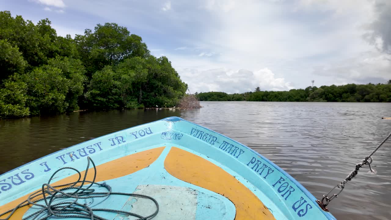 A boat sailing through Negombo Lagoon with a view of a small forested island, capturing a serene and peaceful landscape scene.