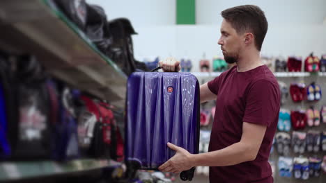 hombre eligiendo una maleta en una tienda
