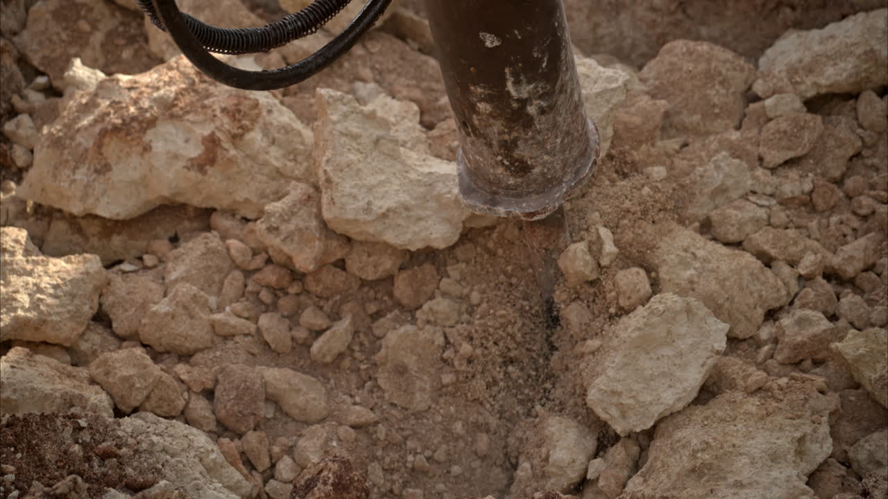 지하에 구을 파는 동안 부서진 바위를 움직이는 수압 망치의 느린 움직임 클로즈업