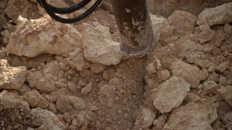 slow motion close up of an hydraulic hammer moving broken rocks while digging a hole in the ground