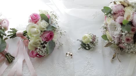 beautiful wedding bouquets lie with wedding rings near window on white curtains