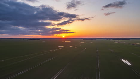 Cultivos-De-Tierras-De-Cultivo-Bajo-Una-Puesta-De-Sol-Dorada---Hiperlapso-Aéreo-De-Paisaje-Nublado