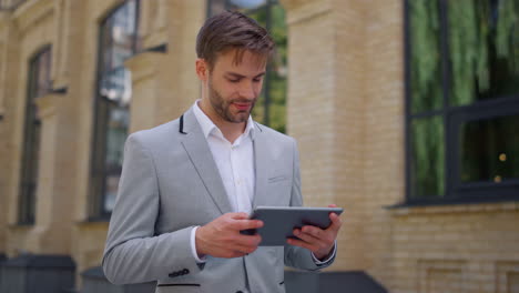 surprised man using tablet on move. businessman reading message device outside