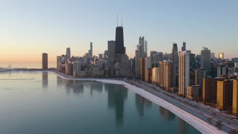 chicago skyline reflects off of lake michigan during freezing cold winter sunrise