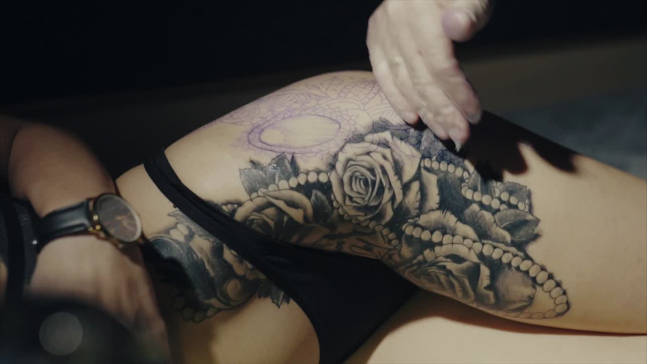 Woman getting a thigh tattoo