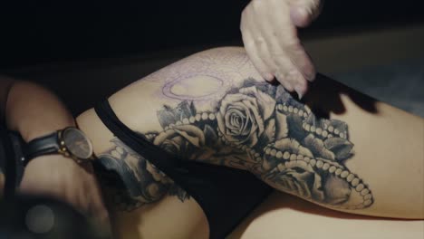 mujer haciendo un tatuaje en el muslo
