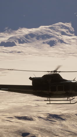 helicopter flying over a snow-covered mountain range