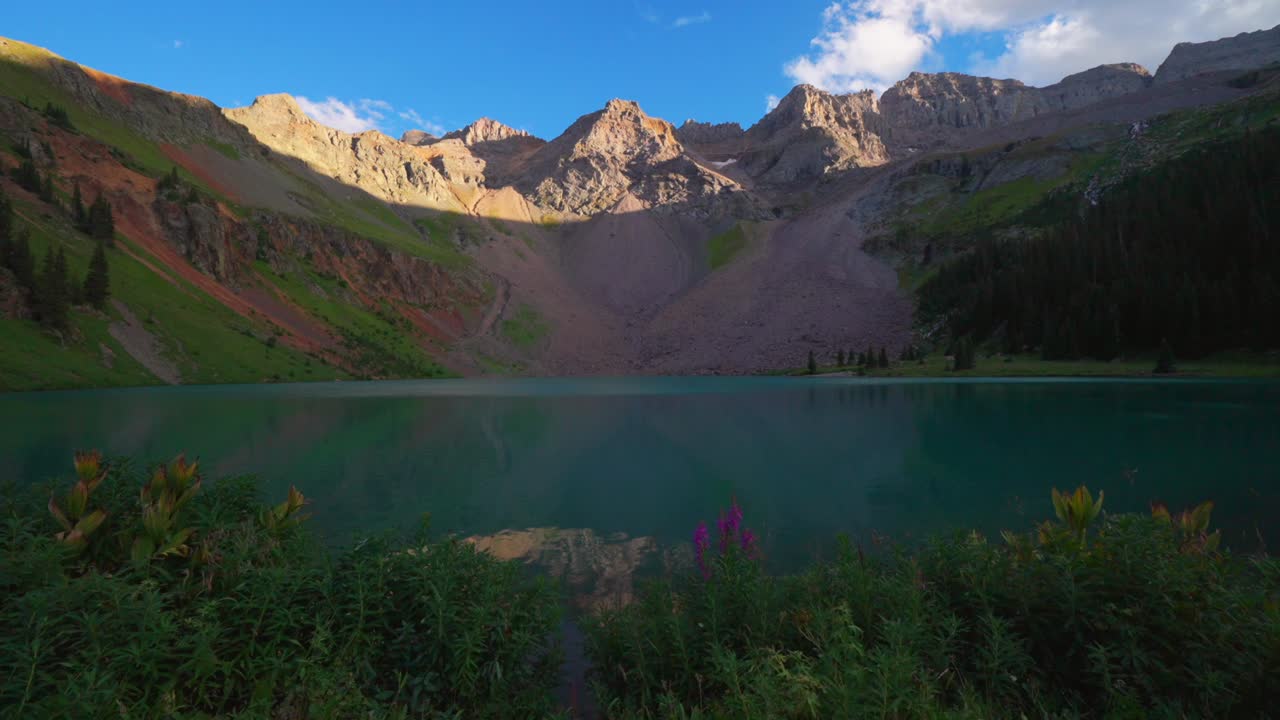 Lower Blue Lake Mount Sneffels Wilderness summer sunset golden hour Ridgway Telluride Colorado wildflowers shore sunset San Juan Rocky Mountains Uncompahgre National Forest clear sky clouds pan right