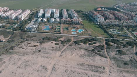 vista de drones de la montaña con molinos y urbanización en primera línea de playa en la hermosa playa de cádiz con arena blanca y olas para surfear