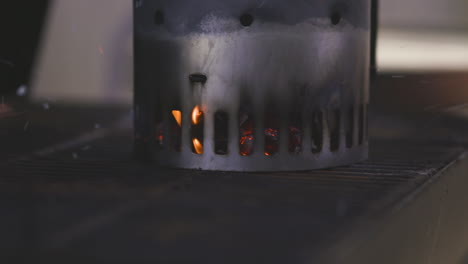 charcoal chimney starter heating up and flaming on a grill at a barbecue in a public park in summer