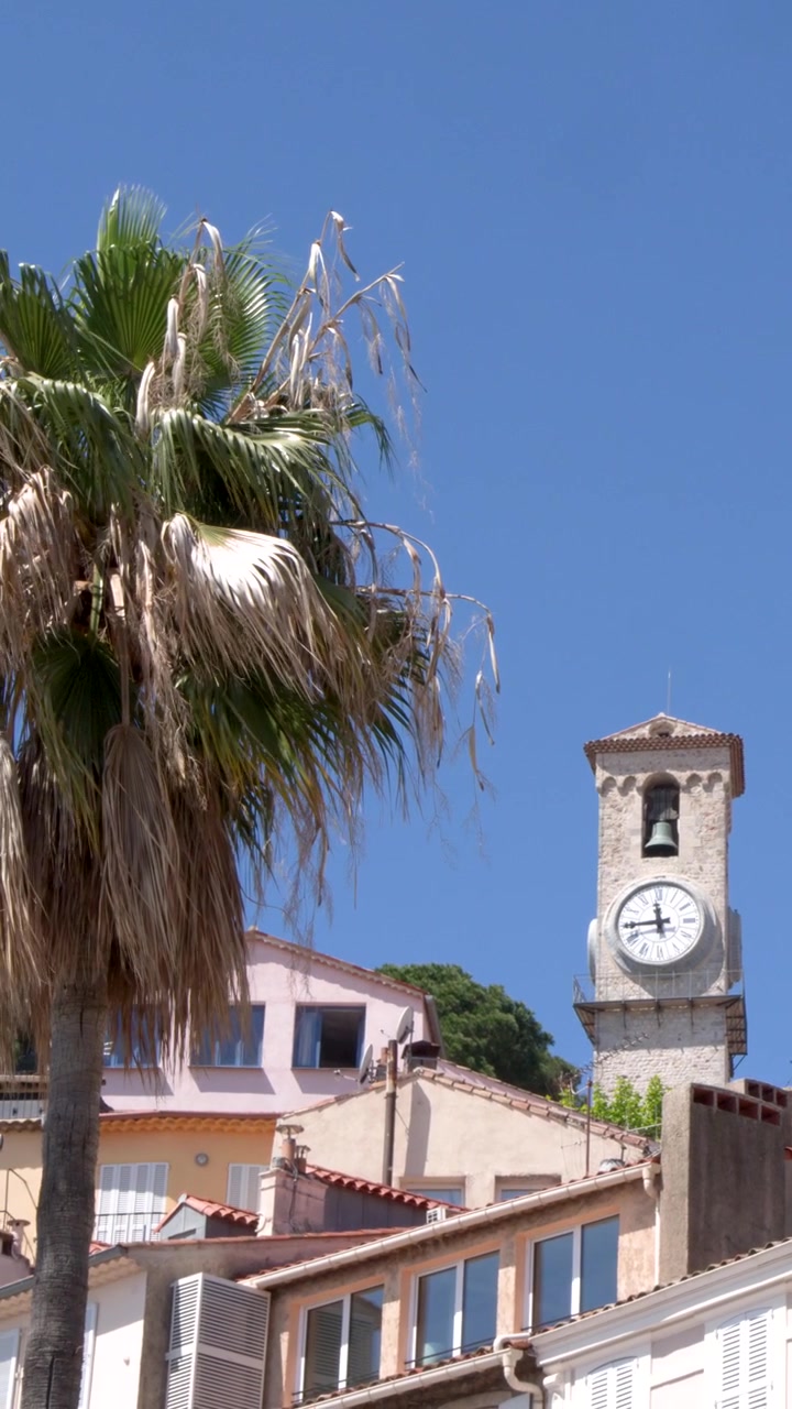 Antica torre dell'orologio in pietra che si erge sopra gli edifici di una città mediterranea
