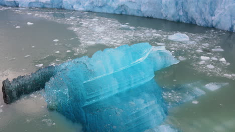 un avión no tripulado gira alrededor de un iceberg flotante que se derrite en el glaciar dawes, el fiordo del brazo de endicott, alaska