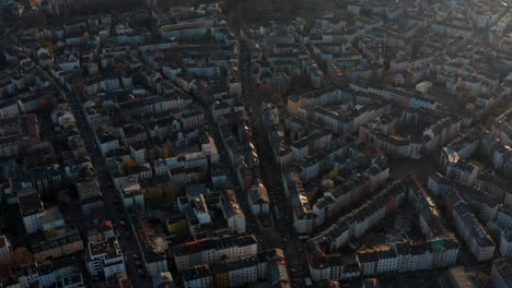 Aerial-view-of-buildings-and-streets-of-Bornheim-neighbourhood.-Tilt-up-slowly-revealing-skyline-with-skyscrapers-downtown-at-river-winding-through-city.-Frankfurt-am-Main,-Germany