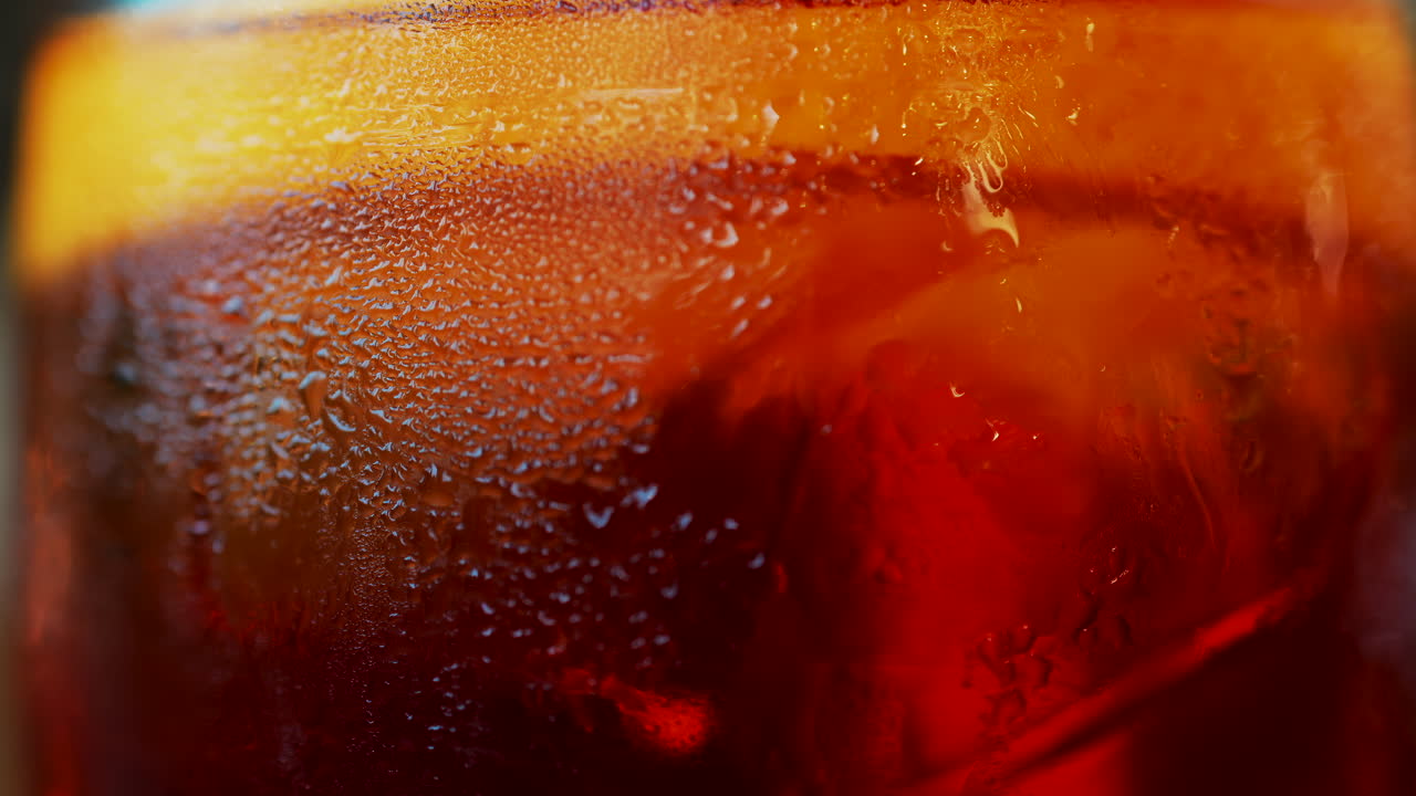 Close up of a Negroni cocktail with orange slice and ice cubes on a wooden table