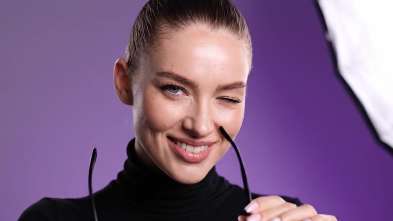 A Confident Model Showcases Bold Sunglasses and Stylish Fashion in a Glamorous Studio Photoshoot with a Vibrant Purple Background