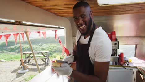 retrato de un hombre afroamericano sonriendo mientras prepara salchichas en el camión de comida