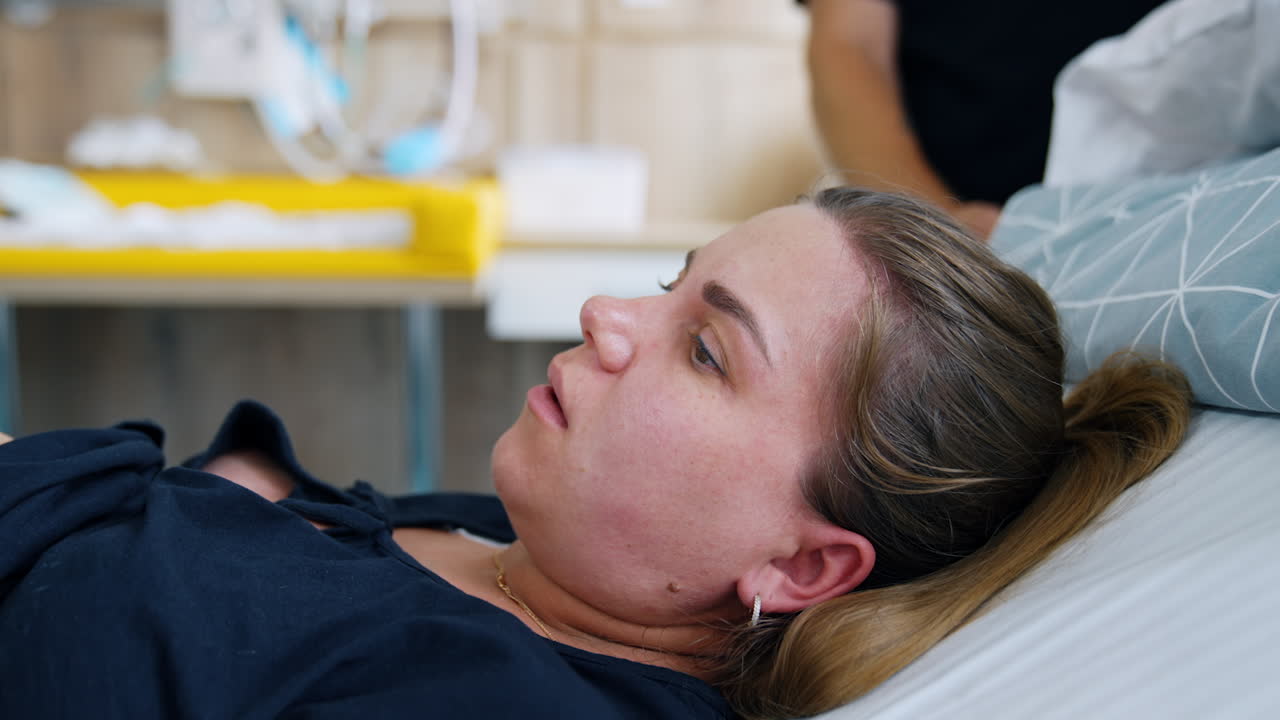 Caucasian woman delivering a baby. Lady is trying to push her child and her face becomes red. Close up.