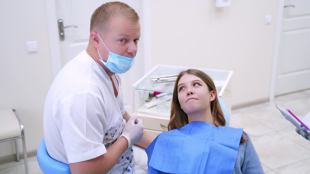 Dentist talks to a female patient. Professional doctor explains female patient how to look after her teeth. Beautiful woman visits stomatologist in clinic.
