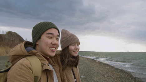 바람 부는 날 바다를 바라보며 이야기하는 해변에서 겨울 옷을 입은 두 십대의 모습을 가까이서 볼 수 있습니다