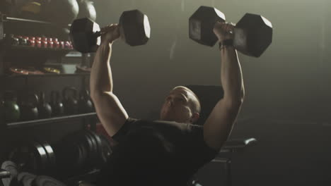 man performing dumbbell chest press exercise in a gym