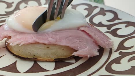 poached eggs with ham and crumpet opened and running over plate