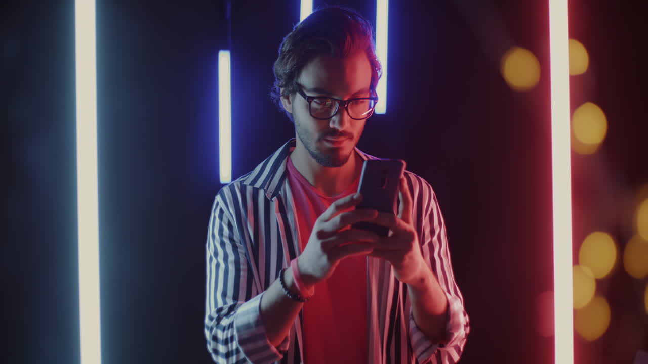 Man Looking at Phone in Neon Light
