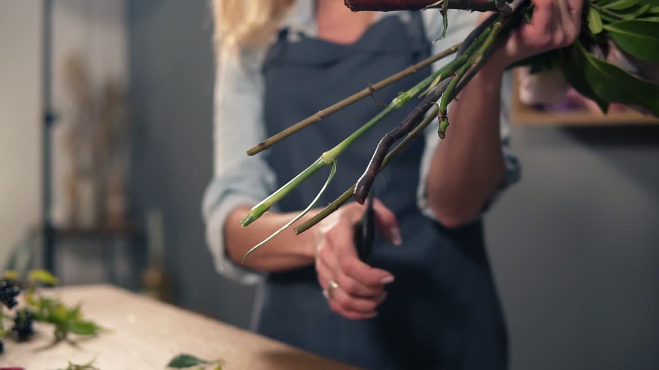 artista floral profesional preparando un ramo, florista cortando tallos de flores en el tiro de flores. floristería, hecha a mano y pequeña