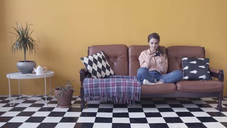 mujer relajándose en el sofá, usando el teléfono