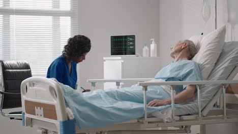 a black woman cardiologist doctor is talking to an old man patient lying on a hospital bed discussing rehabilitation after recovery. an infectious disease neurologist discusses a treatment strategy