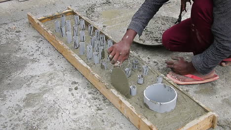 indian mason worker placing wet concrete mix into a slab around pipes, leveling with trowel for smoothness