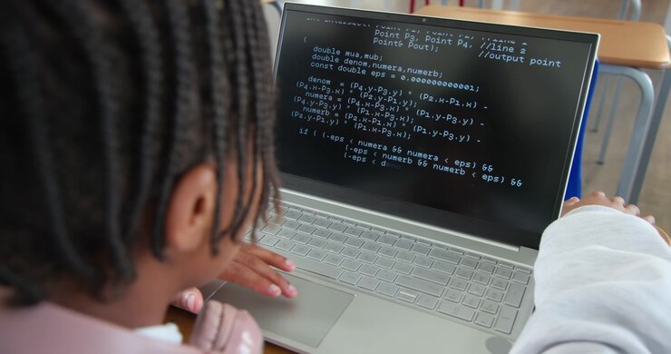 African youth male leaning in, using trackpad, reviewing code on laptop at school desk, copy space