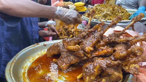 proveedor marinando trozos de pierna de cordero en salsa de curry para la gente en el bazar chowk en dhaka