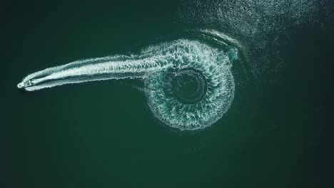 aerial bird view of a speedboat after riding in a circle and going straight to create a beautiful round path in the sea