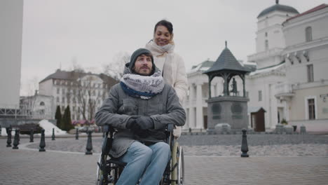 muslim woman taking her disabled friend in wheelchair on a walk around the city in winter 1