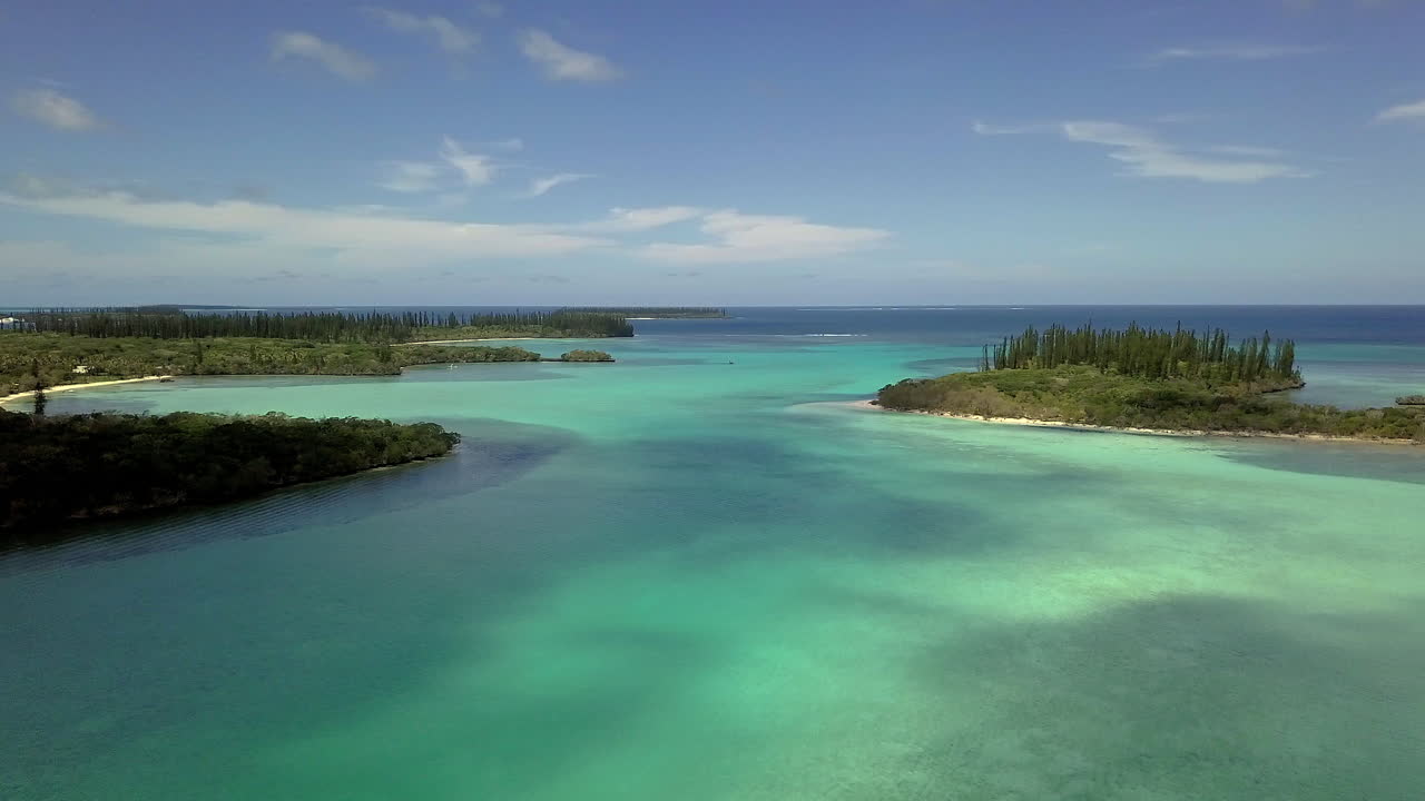 Aerial orbit reveal of islands and shallow water. New Caledonia