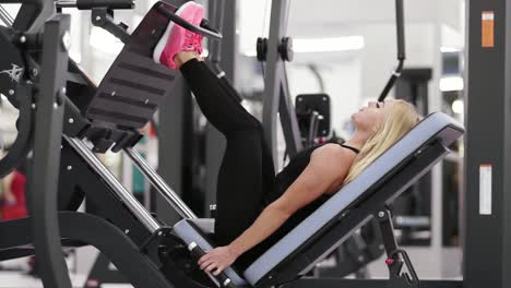 Young-beautiful-blond-female-working-out-at-the-gym.-Building-up-strong-glutes,-hamstrings-and-hips-on-leg-press-mashine.-Fitness-lifestyle.