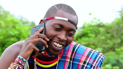 hombre africano feliz, sonriendo, hablando por teléfono, usando ropa tradicional masai