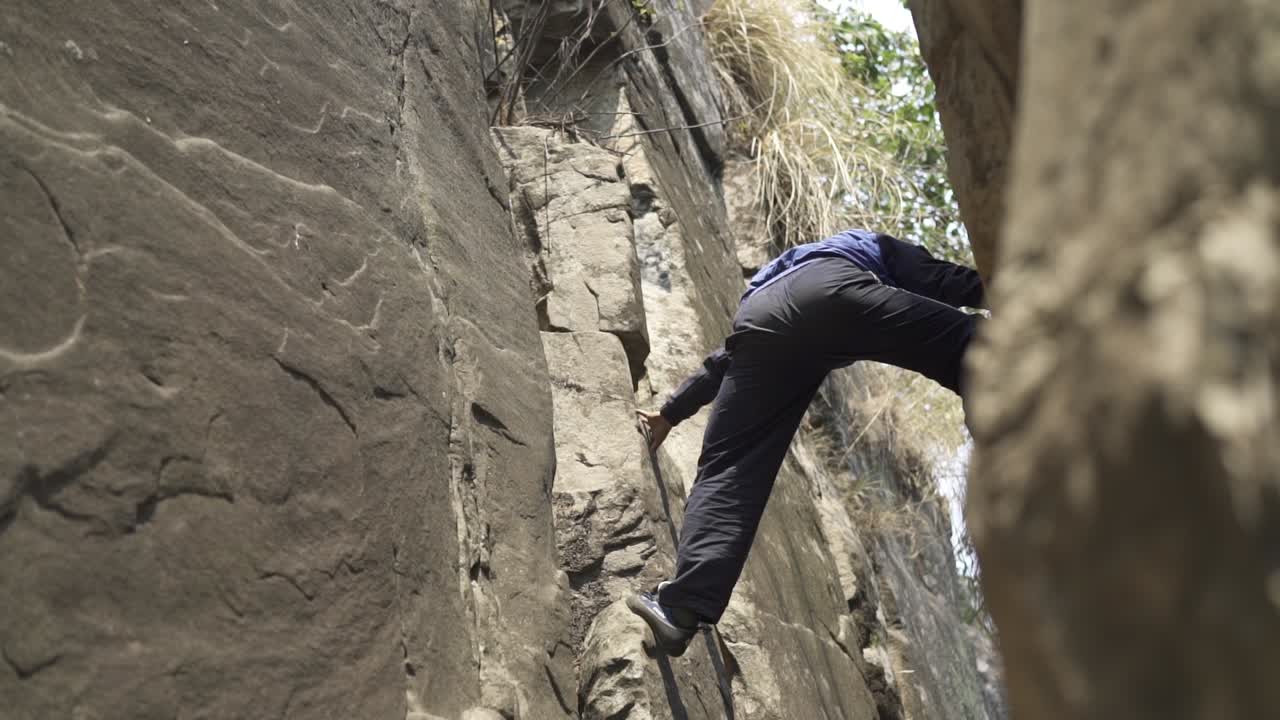 un joven aventurero escalando una montaña sin apoyo.