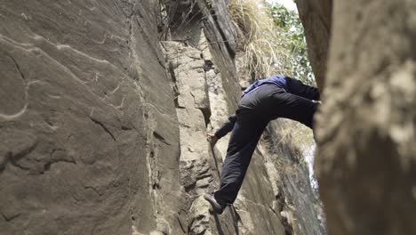 adventurous young man climbing a mountain without support