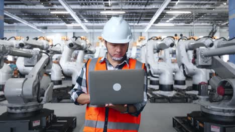 ingeniero trabajando con brazos robóticos en una fábrica