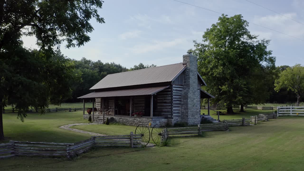 4K aerial of rustic log cabin surrounded by old wooden fence in rural south