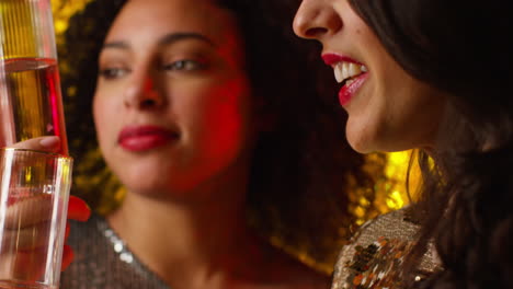 close up of two women in nightclub or bar celebrating drinking alcohol with sparkling lights 5