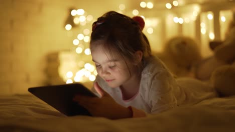 chica usando la tableta en la cama por la noche