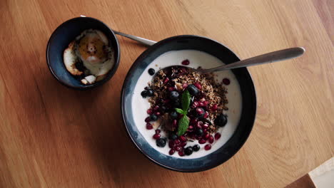 tazón de desayuno de granola y huevo frito sobre una mesa de madera en casa