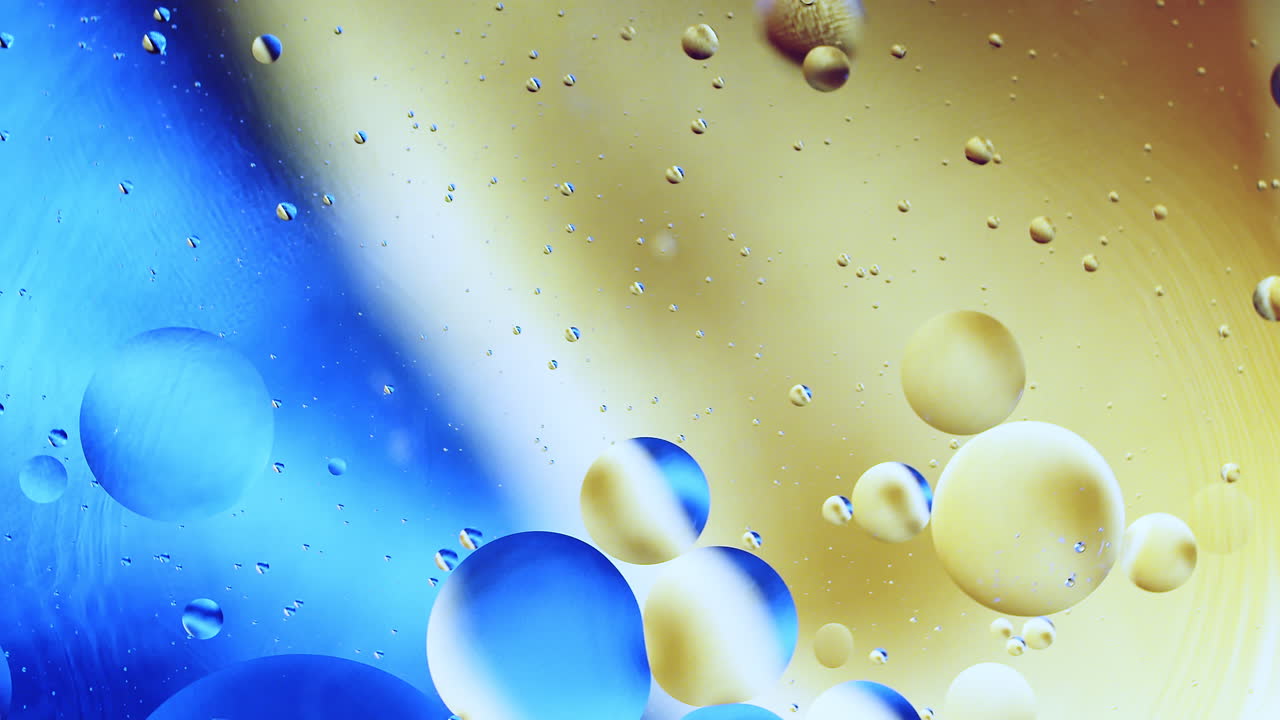 Real close up oil bubbles in water rotation with color gradient abstract mixing background.